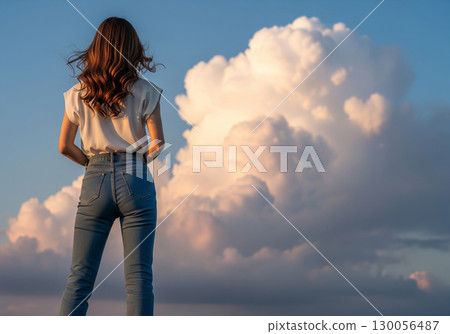 一位身穿牛仔布的女子凝視著夕陽色的積雨雲 130056487