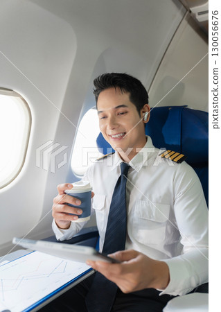 Portrait of a trained airplane captain in uniform preparing to fly in a simulator cockpit. 130056676
