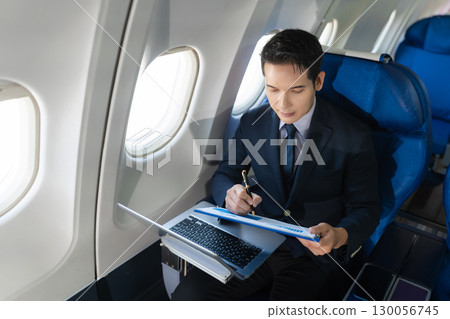 Traveling and technology. young business man working on Laptop and smartphone while sitting in airplane. 130056745