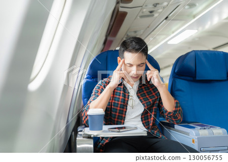 Sad asian male with headache feeling sick while sitting in the airplane , Passengers near the window. 130056755