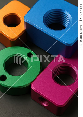 Colorful anodized aluminum mechanical parts with threaded holes and smooth surfaces arranged on dark background Colorful anodized aluminum mechanical parts with threaded holes and smooth surfaces arranged on dark background 130057453