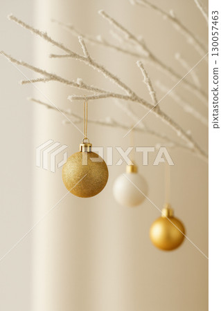 Minimal winter decoration with gold and white baubles hanging from frosted branches in soft morning light evokes calm festive mood 130057463