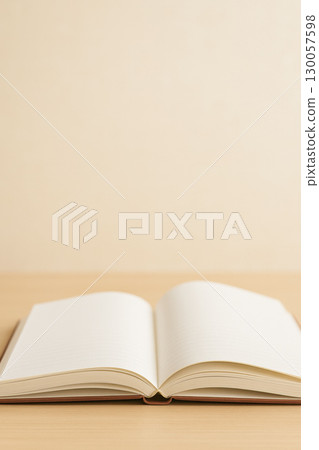 Open notebook with blank lined pages on wooden surface with soft warm light creating calm and inviting atmosphere for writing or study 130057598