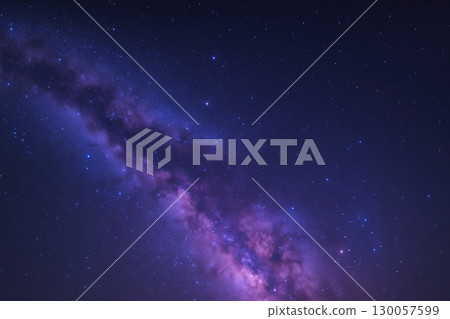 Milky Way galaxy with vibrant purple and blue hues stretches across starry night sky, creating stunning deep space view 130057599
