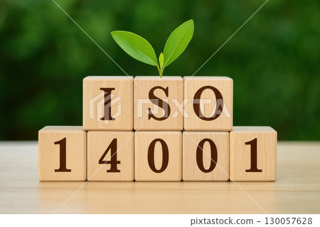 Wooden cube blocks arranged to display ISO 14001 with fresh green plant sprout symbolizing environmental management and sustainability concept 130057628
