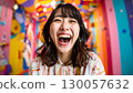 一位年輕可愛的日本女子在色彩繽紛、明亮的房間裡大笑 130057632