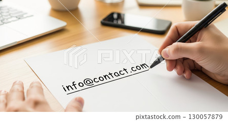 Hand writing email address on white paper. Contact us concept for customer service and business communication. Person sending information with pen 130057879