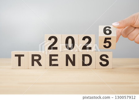 Hand flipping wooden block to change year from 2025 to 2026 over TRENDS word for new business concepts ahead 130057912
