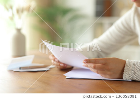Woman hand reading card on table in a house interior 130058091