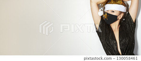 Woman with gold christmas hat, black medical mask. Fashion shiny style for xmas time. Protection from flu on holidays 130058461
