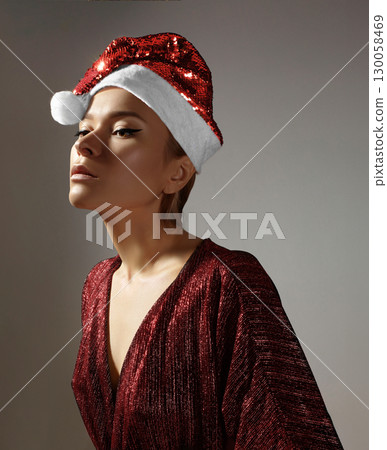 Woman with red christmas hat, black medical mask. Fashion shiny style for xmas time. Protection from flu on holidays Woman with red christmas hat, black medical mask. Fashion shiny style for xmas time. Protection from flu on holidays 130058469