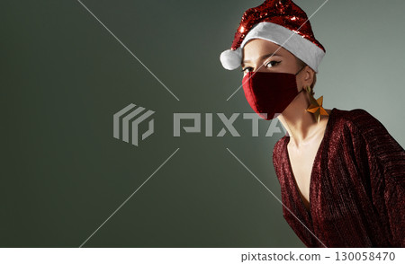 Woman with red christmas hat, red medical mask. Fashion shiny style for xmas time. Protection from flu on holidays Woman with red christmas hat, red medical mask. Fashion shiny style for xmas time. Protection from flu on holidays 130058470