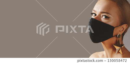 Beautiful Woman with Black Face Mask. Fashion Eye Make-up and Gold Accessories. Protection hygiene in virus pandemic 130058472