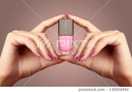 Manicured nails with pink nail polish. Manicure with bright nailpolish. Fashion manicure. Shiny gel lacquer in bottle 130058492