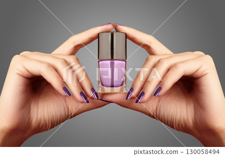 Manicured nails with lilac nail polish. Manicure with bright nailpolish. Fashion manicure. Shiny gel lacquer in bottle 130058494