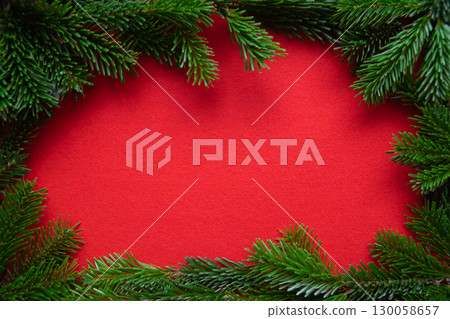 Red bright Christmas background. Winter frame of green branch on the textured fabric background.  130058657