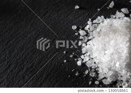 Salt crystals for cooking the food. Pile of sea salt on a black natural background. Salt crystals for cooking the food. Pile of sea salt on a black natural background. 130058661