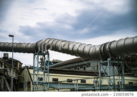 A huge silver pipeline crossing an industrial area 130059076