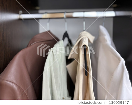 Business and casual clothes hanging on hangers in closet, womens wardrobe organization, womens fashion and clothing care 130059147