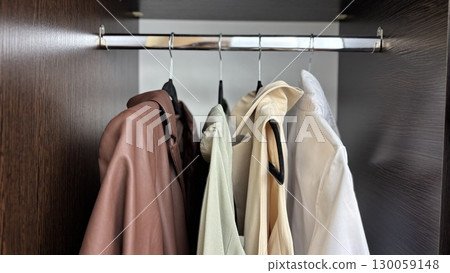 Business and casual clothes hanging on hangers in closet, womens wardrobe organization, womens fashion and clothing care Business and casual clothes hanging on hangers in closet, womens wardrobe organization, womens fashion and clothing care 130059148