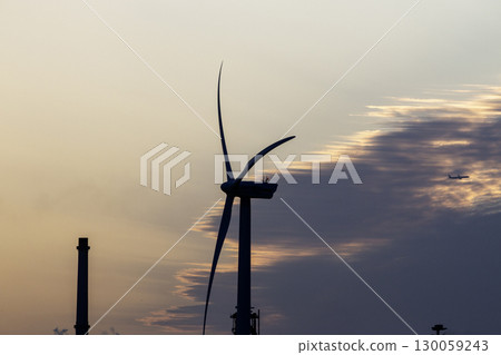 Wind Turbine Silhouetted Against Sunrise Sky With Distant Airplane in Denmark Wind Turbine Silhouetted Against Sunrise Sky With Distant Airplane in Denmark 130059243