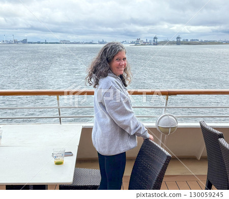 Woman Enjoying Vacation having a Drink on a Cruise Ship on a Cloudy Day 130059245