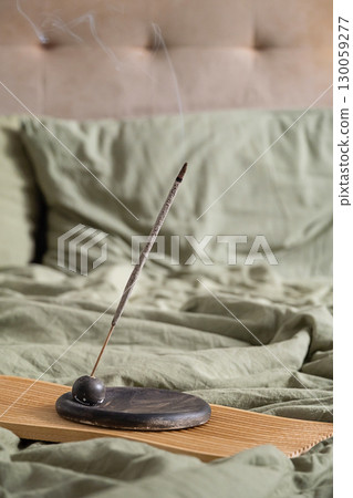 Burning incense stick on wooden tray with smoke rising. Burning incense stick on wooden tray with smoke rising. 130059277