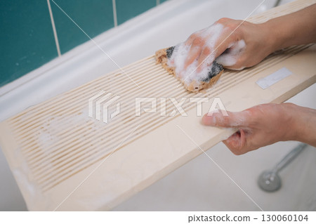 Cleaning detachable air conditioner filter with sponge, professional housekeeper maintaining hygienic bathroom environment and removing dust buildup. Concept of air condition hygiene. 130060104