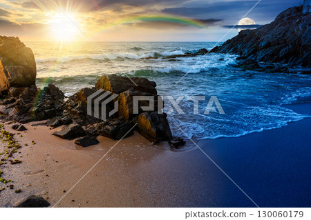 landscape by the sea in summer. day and night time change concept. beautiful beach with rocks washed by calm waves with sun and moon at twilight. view to horizon under blue sky with clouds 130060179