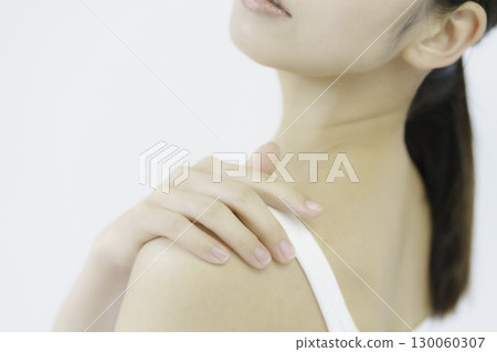 Close-up of a young woman's hand touching her shoulder against a white background Close-up of a young woman's hand touching her shoulder against a white background 130060307