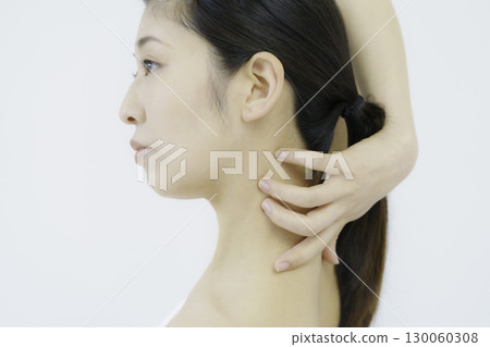 Close-up of a young woman's face touching her nape against a white background Close-up of a young woman's face touching her nape against a white background 130060308