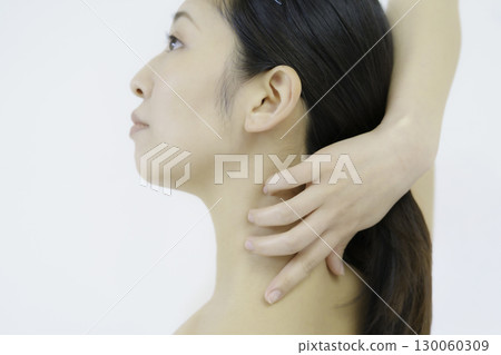 Close-up of a young woman's face touching her nape against a white background Close-up of a young woman's face touching her nape against a white background 130060309