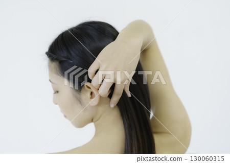 Young woman showing nape with hand in hair against white background 130060315