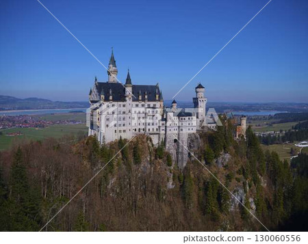 Bavarian castle perched on a hilltop with clear blue sky and distant lake view Bavarian castle perched on a hilltop with clear blue sky and distant lake view 130060556