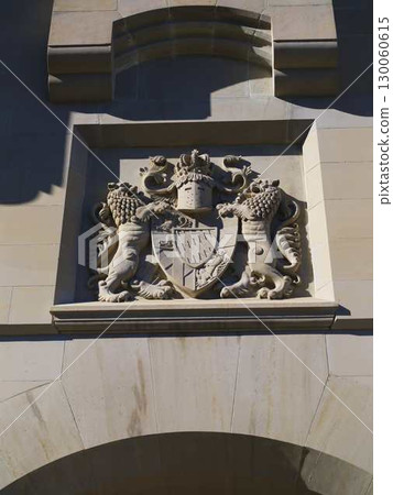 Historic stone emblem featuring lions and a shield displayed on a building facade in bright sunlight Historic stone emblem featuring lions and a shield displayed on a building facade in bright sunlight 130060615