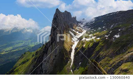 Majestic mountain peak with lush green valleys under a clear blue sky in Switzerland during summer 130060840