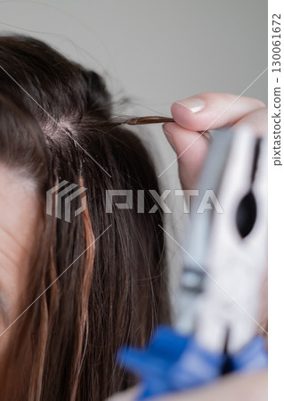 Woman in beauty salon having hair extensions carefully removed by professional hairstylist 130061672