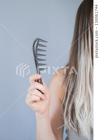 Gentle care for hair extensions young woman using wide tooth comb for safe and easy styling in beauty salon 130061744