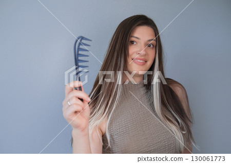 Beautiful hair extensions woman using comb for gentle and comfortable hair care in professional beauty salon 130061773