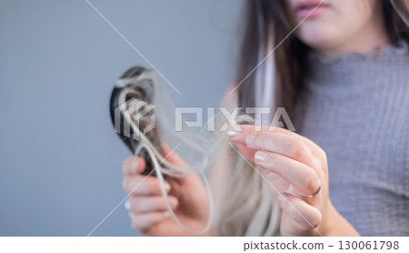 Young woman with hair loss holding hairbrush with strands showing weak brittle hair and hair breakage problem 130061798