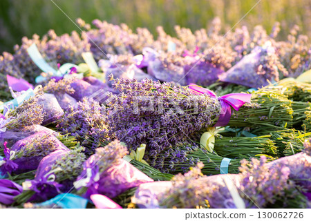 Bouquets and sachets of fresh lavender tied with ribbons of lilac colour on the table. Seasonal harvesting of plants, scented beautiful flower, bright sunny day Bouquets and sachets of fresh lavender tied with ribbons of lilac colour on the table. Seasonal harvesting of plants, scented beautiful flower, bright sunny day 130062726