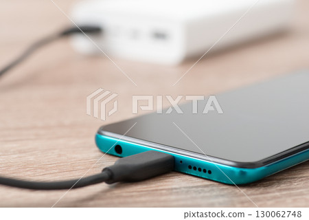 Charging phone via usb cable, powerbank on the background. Using power bank for charging devices concept 130062748