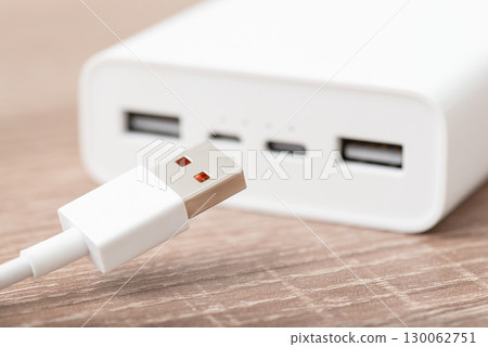 Close up of power bank with usb type-a cable on the foreground. Using powerbank for charging devices Close up of power bank with usb type-a cable on the foreground. Using powerbank for charging devices 130062751
