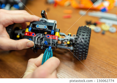 Close up of hands of a boy playing with constructor, making car or robot. Child playing with technological constructor 130062774
