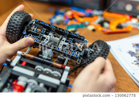 Boy playing with constructor, attaching wheel to the car. Building complex mechanisms with modern engineering constructor 130062778