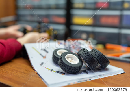 Focus on four wheels of constructor laying on building plan on the table. Playing with modern constructor Focus on four wheels of constructor laying on building plan on the table. Playing with modern constructor 130062779