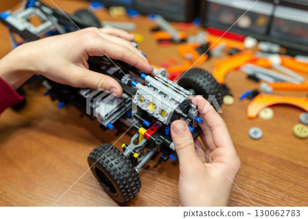 Boy building robot car with electronic constructor. Boy learning basics of engineering by playing with modern technological constructor Boy building robot car with electronic constructor. Boy learning basics of engineering by playing with modern technological constructor 130062783