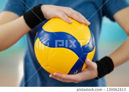 Bright new volleyball ball in hands of a young girl player. Beautiful photo of a new professional ball in female hands on court Bright new volleyball ball in hands of a young girl player. Beautiful photo of a new professional ball in female hands on court 130062813