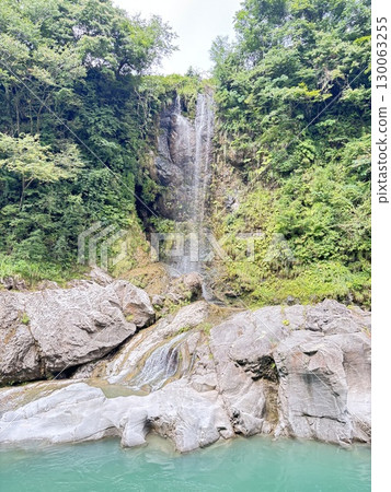 一個隱藏的瀑布，周圍環繞著新鮮的綠色植物 130063255