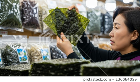 Asian woman examining seaweed sheets at grocery store 130064059